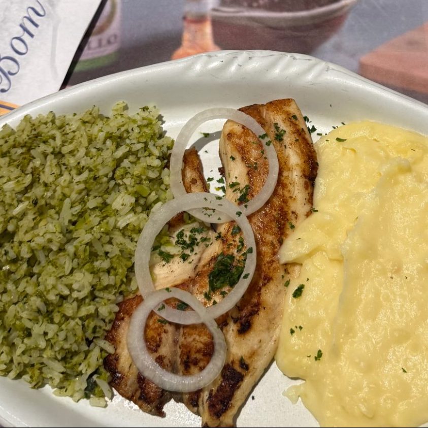 Prato com peixe grelhado, cebola, arroz verde e purê